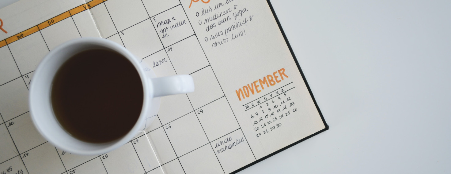Cup of coffee sitting on top of an open planner with goals for the month outlined