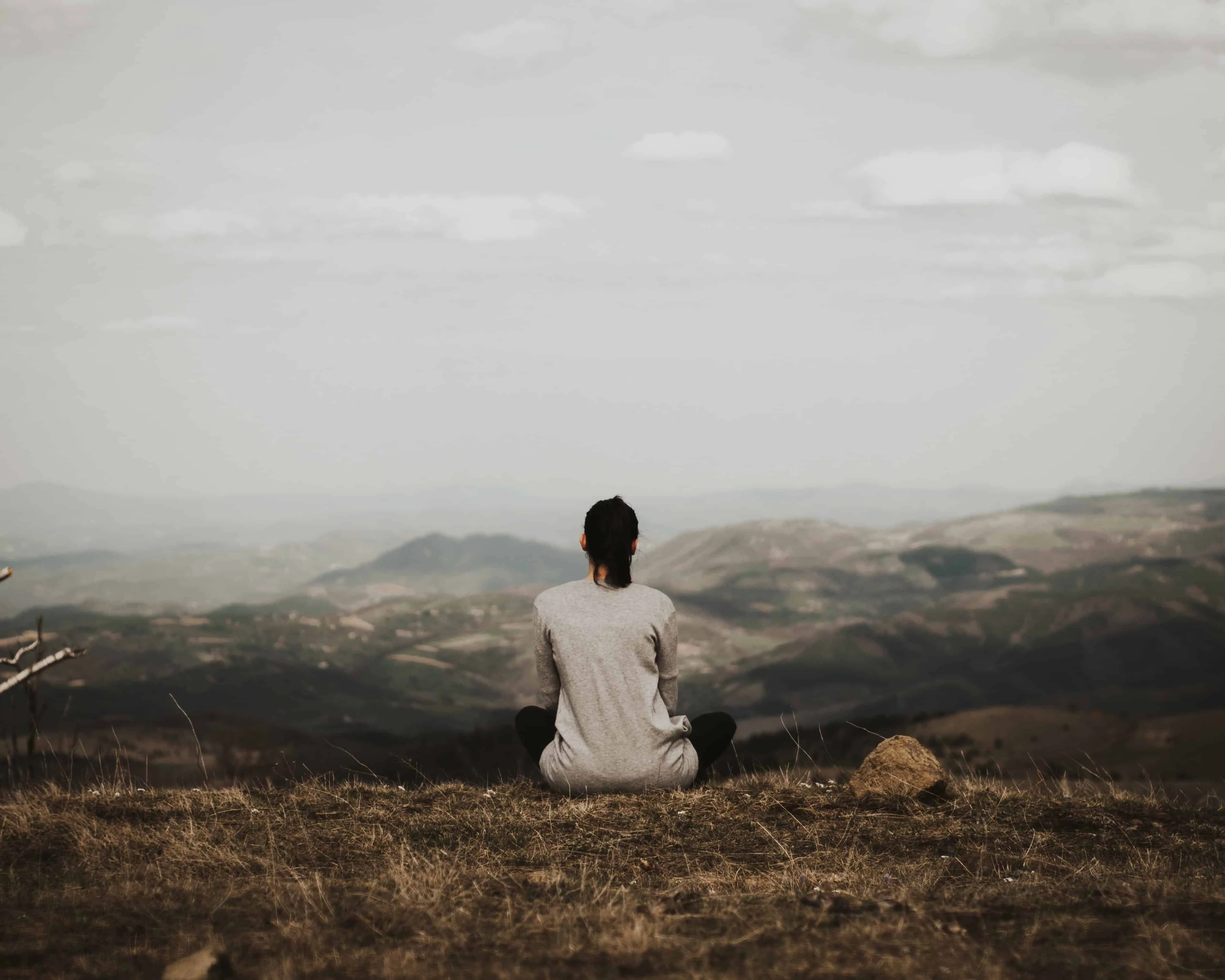 Woman meditating on top of a hill